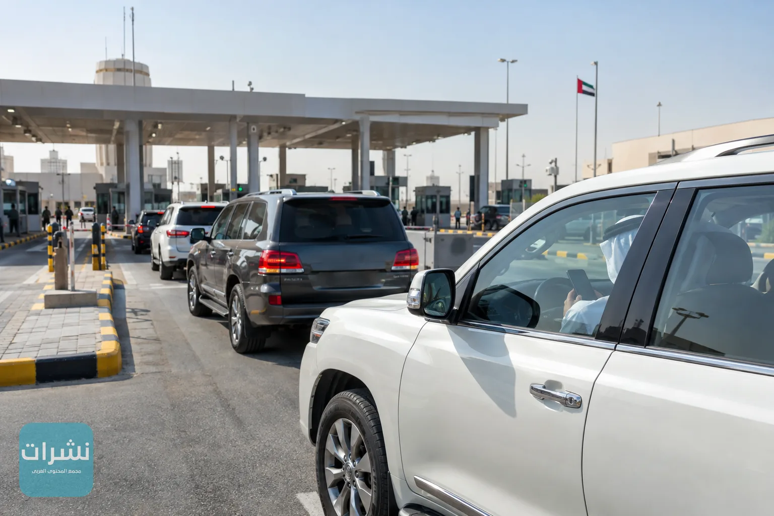 مركبات تصطف في مسار أحد المنافذ البرية، وأحد الركاب ينظر إلى هاتفه في الصباح